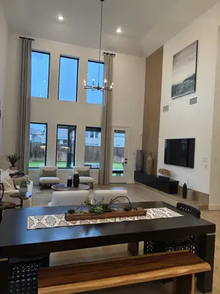 Model Home A spacious living room with high ceilings, large windows, modern decor, and a cozy seating area.