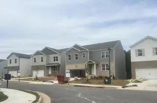 Modern grey and brick homes on a serene street in Oaks at Cedar Grove by D.R. Horton (Fairburn, GA).