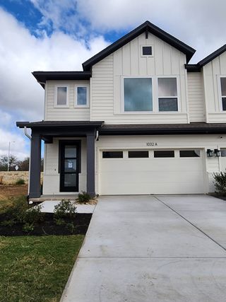 A modern white home with black trim and a pristine driveway in Easton Park - Nelson Village 29’ by David Weekley Homes (Austin, TX).