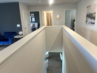 A cozy hallway with neutral walls, wooden floors, and a blue accent chair leading to stylish bedrooms.