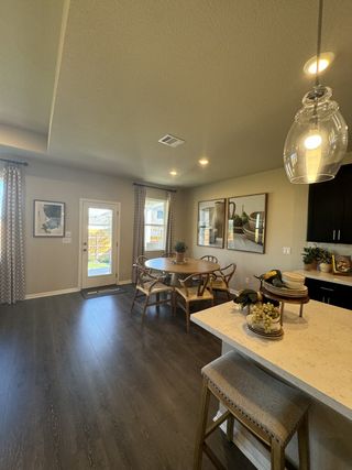 A bright dining area with modern wood furnishings, patterned curtains, and an open flow to the outdoor patio.