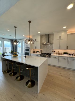 A modern kitchen with sleek cabinetry, an elegant island with gold stools, pendant lights, and ample natural light.