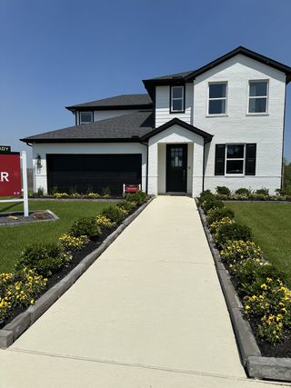 A modern white brick home with sleek black accents and lush landscaping in Montgomery Ridge: Founders Collection by Beazer Homes (Montgomery, TX).