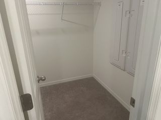 A spacious walk-in closet with soft carpet, wire shelving, and a neutral color palette.
