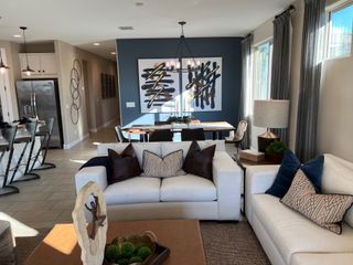 A modern living and dining area featuring chic art, plush seating, and elegant decor with abundant natural light.