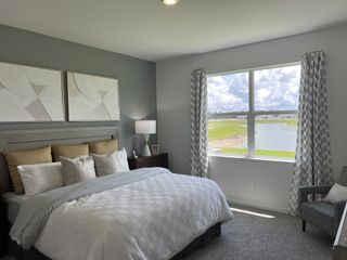 Model Home A serene bedroom with elegant decor, neutral tones, and a picturesque window view of a tranquil lake.