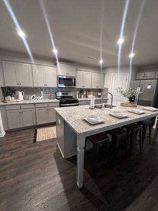 Model Home A modern kitchen with elegant gray cabinetry, a large granite island, and sleek appliances, perfect for family gatherings.