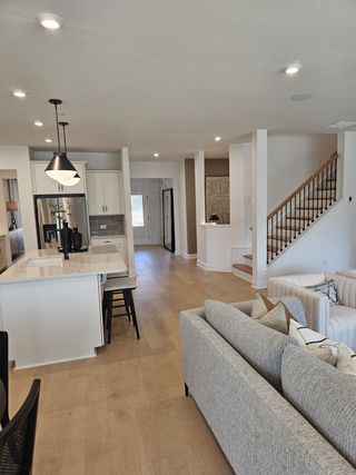 An open-concept living area with light wood flooring, sleek kitchen, and cozy gray sofas creating an inviting space.
