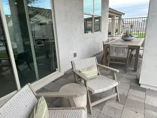 A cozy patio with woven chairs, tiled floor, and a stylish dining set for outdoor gatherings.