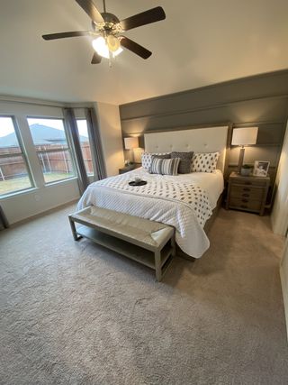 A cozy bedroom with a tufted headboard, plush carpet, and elegant bedside lamps.