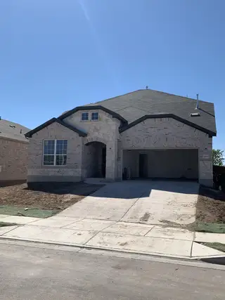 Street view A charming stone home with a spacious driveway in Lagos by Pulte Homes (Manor, TX).