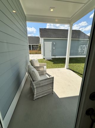A cozy covered patio with wicker seating and a view of the backyard and detached garage, creating a relaxing outdoor space.