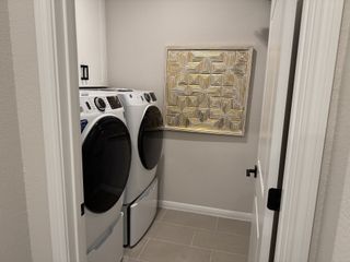 A modern laundry room with front-loading washer and dryer, sleek cabinetry, and abstract wall art.