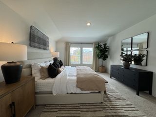 A cozy bedroom featuring a plush bed, modern decor, and ample natural light, complemented by sleek black accents and greenery.