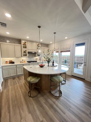 A modern kitchen featuring a spacious island, elegant cabinetry, and sleek pendant lighting with natural light.