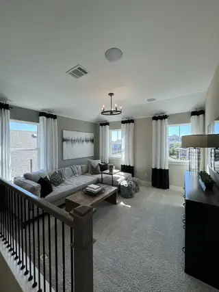 A cozy living area featuring a modern sectional, chic decor, and ample natural light through elegant windows.