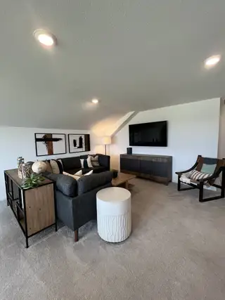A contemporary living room featuring a sleek gray sofa, modern decor, and stylish furnishings on a plush carpet.