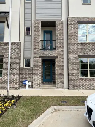 A modern brick facade with a blue door and balcony in Collin Creek by Mattamy Homes (Plano, TX).