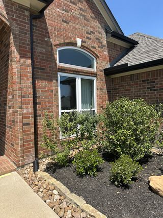 Charming brick home with arched windows and lush landscaping in Walden on Lake Conroe by Legend Homes (Montgomery, TX).