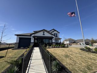 Street view A modern white home with landscaped yard in Enclave at Cele by Saratoga Homes (Pflugerville, TX).