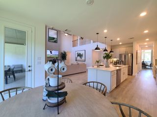 A spacious open-plan kitchen and dining area with sleek lighting, modern decor, and elegant wooden flooring.