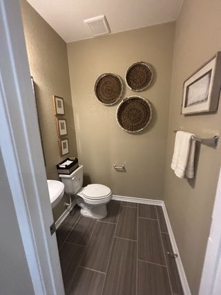 A cozy bathroom with taupe walls, modern art, and sleek tile flooring.