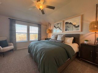 Model Home A cozy bedroom featuring a plush bed, warm lighting, and large windows with airy curtains.