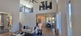 A spacious living area with high ceilings, modern art, and elegant decor creating a bright, inviting atmosphere.