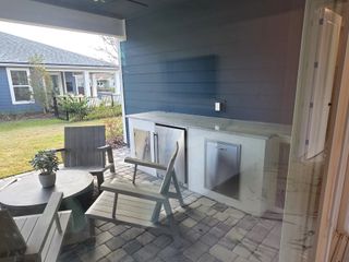 A serene outdoor patio with a built-in grill, cozy seating, and a charming paved backyard space.