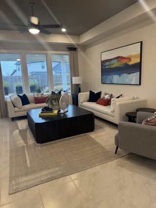 A modern living room with cozy sofas, a large coffee table, abstract art, and abundant natural light from large windows.