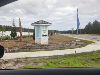 Street view Charming entrance with palms and a welcoming sign at Atlantis Pointe by Dream Finders Homes (Middleburg, FL).