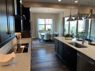 A modern kitchen with dark cabinets, sleek countertops, and pendant lights. Cozy dining area with outdoor views.