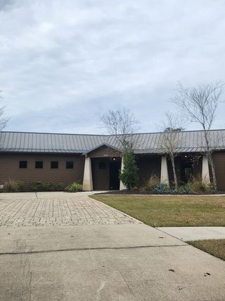 A modern brown home with a metal roof and manicured landscaping in Panther Creek by Brightland Homes (Jacksonville, FL).