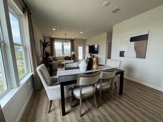 Model Home A cozy dining area with a sleek table, plush chairs, and modern décor, seamlessly flowing into a bright, inviting living space.