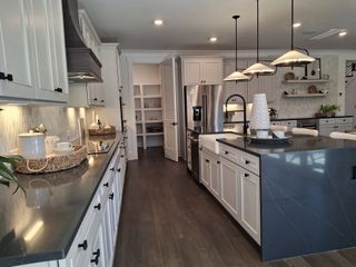 Model Home A spacious kitchen with sleek countertops, elegant lighting, and ample cabinetry, exuding modern sophistication.