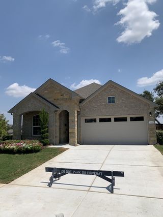 Charming stone home with manicured lawns and a spacious driveway in Bar W Ranch by D.R. Horton (Leander, TX).