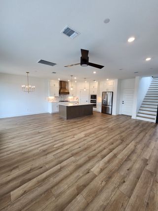An open-concept kitchen with wood floors, modern appliances, pendant lighting, and a central island.