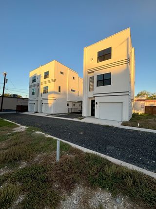 Street view Two modern, white townhomes with clean lines and large windows, part of The Deco by Terramark Urban Homes in San Antonio, TX.