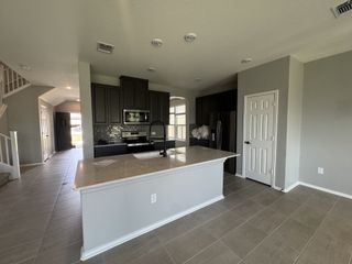 A modern kitchen featuring sleek dark cabinets, a central island with marble countertop, and stainless steel appliances.