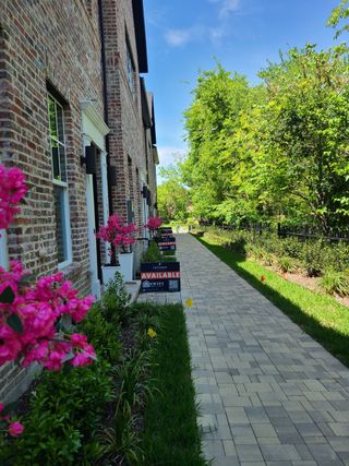 Street view Charming brick townhomes with vibrant landscaping in 1897 Townhomes by InTown Homes (Plano, TX).