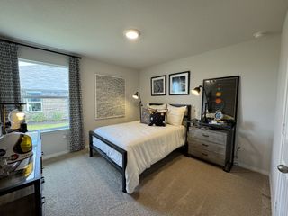 A cozy bedroom with a minimalist black bedframe, space-themed décor, and warm lighting.