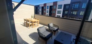 Model Home Modern rooftop patio with sleek seating and a wooden dining set, offering a view of neighboring buildings.