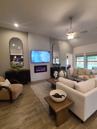 A cozy living room features a modern fireplace, plush seating, and sleek décor with warm, neutral tones.