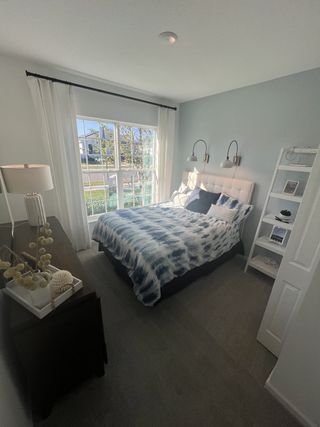 A cozy bedroom featuring a large window, stylish bedspread, sleek lamps, and a light-filled ambiance.