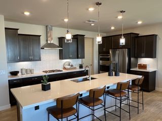 A modern kitchen featuring dark cabinets, a spacious island with seating, stainless steel appliances, and elegant pendant lighting.