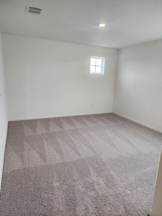 A spacious room with plush carpet, crisp white walls, and recessed lighting for a bright and clean aesthetic.