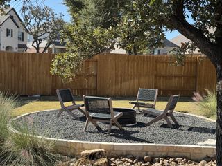 Model Home A cozy backyard fire pit area with modern seating and lush greenery.