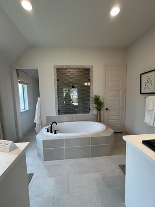 Model Home A contemporary bathroom featuring a hexagonal-tiled tub surround, elegant fixtures, and soft natural accents.