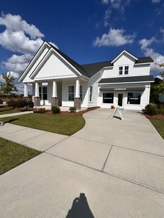 A charming white home with a gable roof and porch in Carnes Crossroads by Lennar (Summerville, SC).