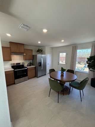 Modern kitchen with stainless steel appliances, wood cabinets, and a cozy dining area featuring a round table and green chairs.